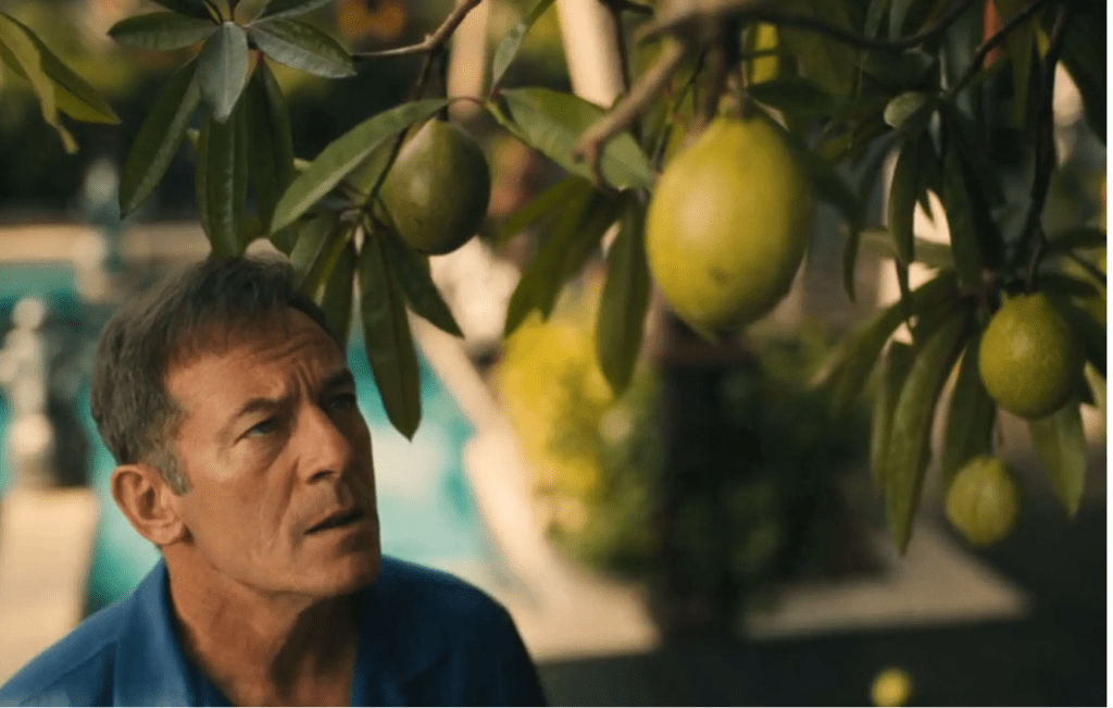 Image of Tim Ratliff (Jason Isaacs) prepares to pick some of the poisonous fruits from the pong-pong fruit in his private villa at The White Lotus resort. Photo by HBO.